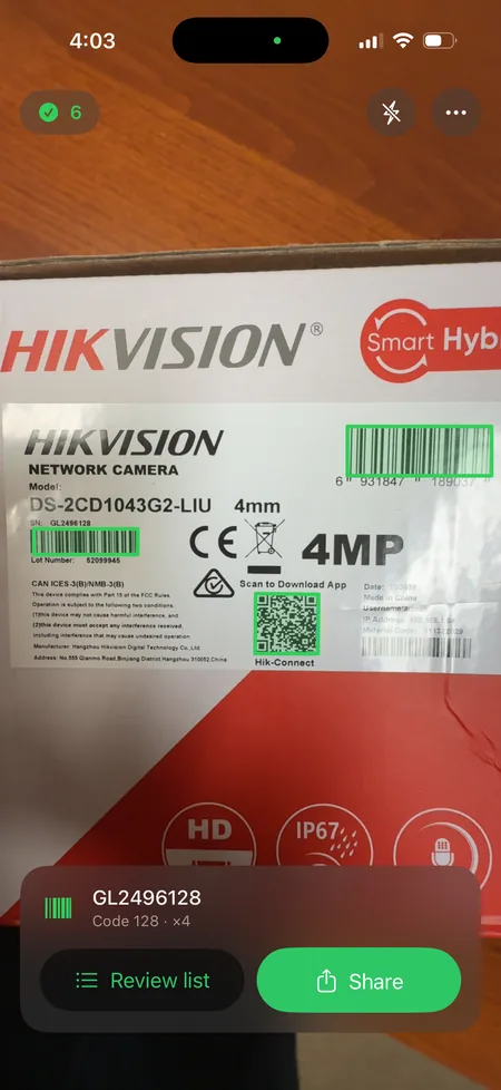 Scan List running on an iPhone: three barcodes and a QR code on a
                  camera box are outlined in green in one pass, with a tally of six
                  codes and the latest value shown at the bottom.